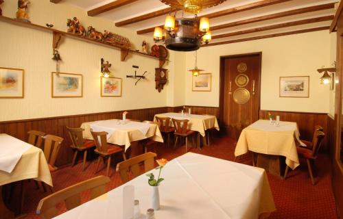 ein Restaurant mit Tischen und Stühlen mit weißem Tischtuch in der Unterkunft Hotel Münchner Löwenbräu in Cuxhaven