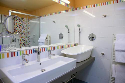 a white bathroom with a sink and a mirror at Kolping Family Resort in Hévíz
