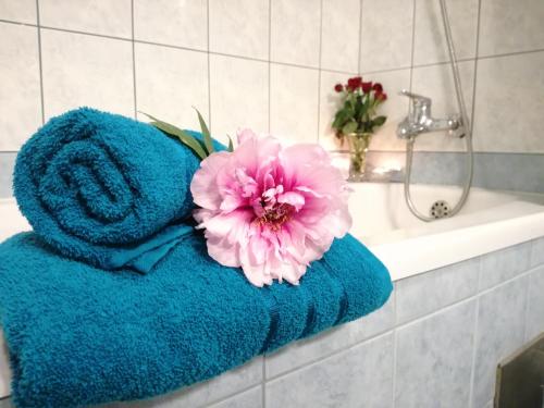 a blue towel with a pink flower sitting on a bath tub at Apartman Una in Crikvenica