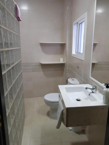 a white bathroom with a toilet and a sink at Hostal Málaga in Arcos de la Frontera