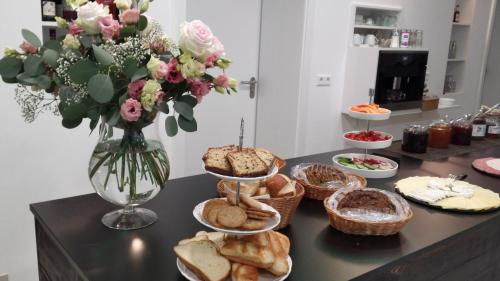 a table with a bunch of bread and a vase of flowers at Boutique-Hotel Kronenstuben in Ludwigsburg