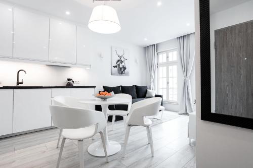 eine weiße Küche und ein Esszimmer mit einem Tisch und Stühlen in der Unterkunft VIU White Moon Apartment in Danzig