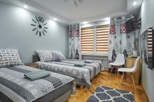 1 dormitorio con 2 camas y reloj en la pared en Apartamenty Lux Relax, en Białystok