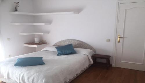 ein Schlafzimmer mit einem Bett mit zwei blauen Kissen darauf in der Unterkunft Villa Bella Portbou in Portbou