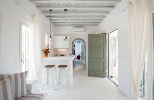 una cucina e un soggiorno con porta verde e sgabelli di Mykonos Cocooning a Panormos - Mykonos