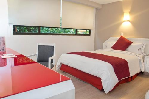 a bedroom with a large bed with a red and white blanket at Hotel Regente in Mexico City
