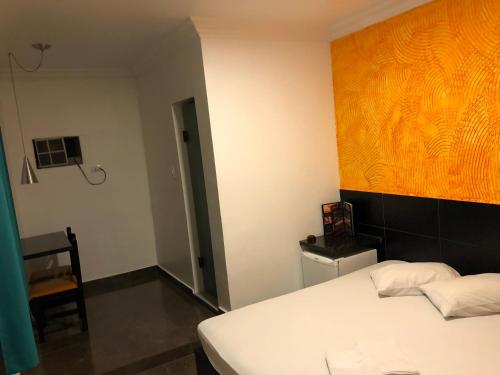 Hotel Romance (Adults Only) في ساو باولو: غرفة نوم بسرير ابيض ولوحة على الحائط