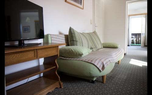 a living room with a tv and a green chair at Appartementhaus Huber in Abersee 