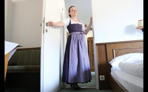 a woman in a dress is standing in a bedroom at Appartementhaus Huber in Abersee 