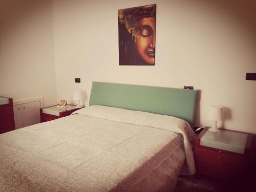 1 dormitorio con 1 cama y una pintura en la pared en Strada dei Frutteti, en Tavullia