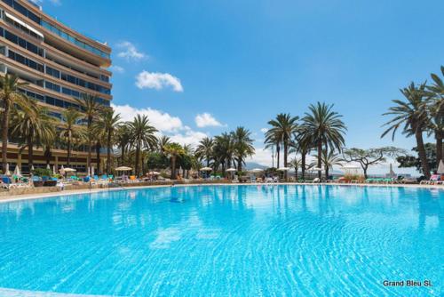 une grande piscine bordée de palmiers et un bâtiment dans l'établissement Marazul del Sur, à Adeje