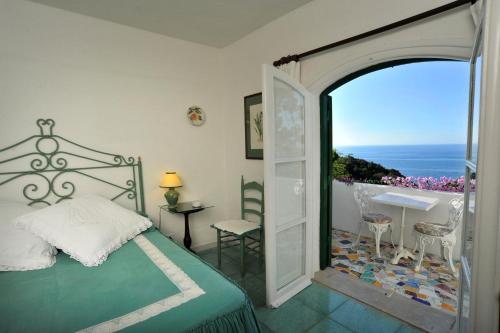 Schlafzimmer mit einem Bett und einer Tür, die auf einen Balkon führt in der Unterkunft Hotel Punta Rossa in San Felice Circeo