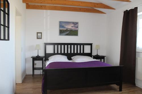 ein Schlafzimmer mit einem schwarzen Bett mit lila Bettwäsche und weißen Kissen in der Unterkunft Zum alten Krug in Wangerland