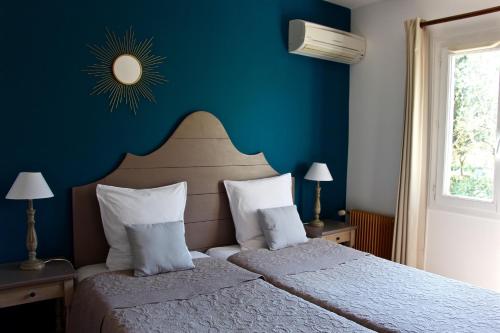 Schlafzimmer mit einem Bett mit blauer Wand in der Unterkunft Hotel Les Oliviers in Draguignan