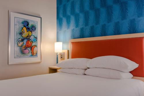 a bedroom with a bed with white pillows at Howard Johnson by Wyndham Anaheim Hotel & Water Playground in Anaheim