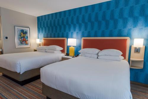 a hotel room with two beds and a blue wall at Howard Johnson by Wyndham Anaheim Hotel & Water Playground in Anaheim