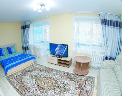 ein Wohnzimmer mit einem Bett und einem TV in der Unterkunft Apart on Slavskogo 14 in Öskemen