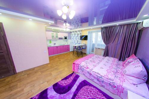 a bedroom with a pink bed and a kitchen at ApartLux on Slavskogo 26 View River in Ustʼ-Kamenogorsk