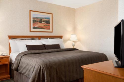 a hotel room with a bed and a flat screen tv at Days Inn by Wyndham Saskatoon in Saskatoon