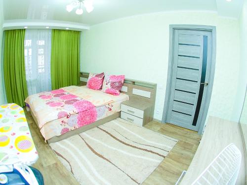 Schlafzimmer mit einem Bett mit rosa und grünen Vorhängen in der Unterkunft ApartLux on Republic Square in Öskemen