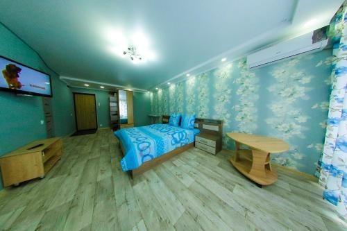 a bedroom with a bed and a table and a tv at Apart Auezov street City Centr in Ustʼ-Kamenogorsk