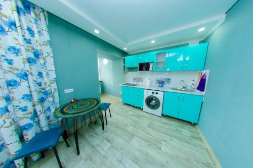 a kitchen with blue cabinets and a table and a sink at Apart Auezov street City Centr in Ustʼ-Kamenogorsk