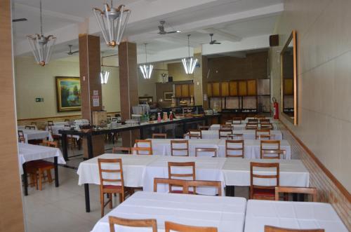 a dining room with white tables and wooden chairs at Presidente Hotel in Poços de Caldas