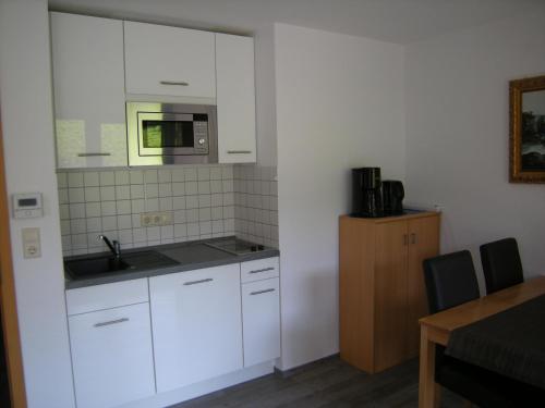 a kitchen with white cabinets and a sink and a microwave at Strandkorb in Horumersiel