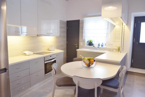 una cucina con tavolo e sedie e una cucina con armadietti bianchi di Christina's Luxury Village House a Plaka Milou