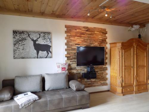 ein Wohnzimmer mit einem Sofa und einem TV an einer Backsteinwand in der Unterkunft Ferienwohnung Hauzenberg Blick in Hauzenberg