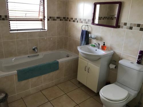 a bathroom with a toilet and a sink and a tub at Sandy Bottoms in Jeffreys Bay