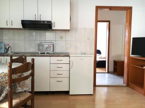 Il comprend une cuisine équipée d'un réfrigérateur blanc et d'une table. dans l'établissement Apartments Savić, à Neum