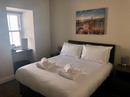 a bedroom with a large white bed with towels on it at The Ships Quarters in Eyemouth