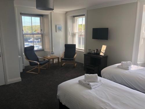 a hotel room with two beds and two chairs at The Ships Quarters in Eyemouth