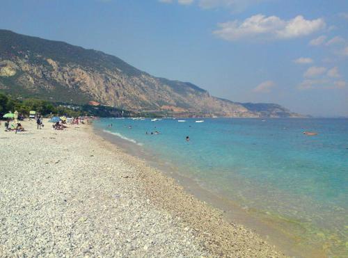 a group of people swimming in the water on a beach at Kineta Apartments in Kineta