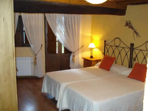 1 dormitorio con 1 cama con sábanas blancas y almohadas rojas en El Balcón de Mogarraz, en Mogarraz