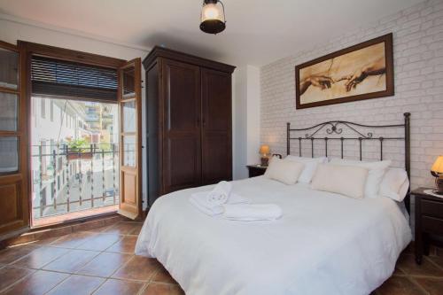 a bedroom with a large white bed and a window at Casita del Realejo in Granada