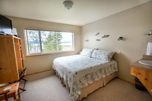 Schlafzimmer mit einem Bett, einem Fenster und einem Waschbecken in der Unterkunft Bay Avenue Inn in Homer