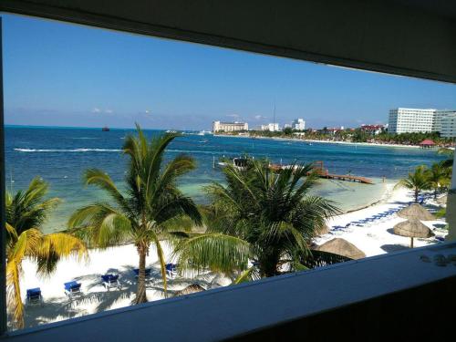 a view of a beach with palm trees and the ocean at Bella Beach Condo Vacation 2 bedrooms in Cancún