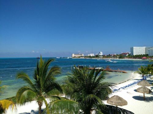 a beach with trees and umbrellas and the ocean at Bella Beach Condo Vacation 2 bedrooms in Cancún