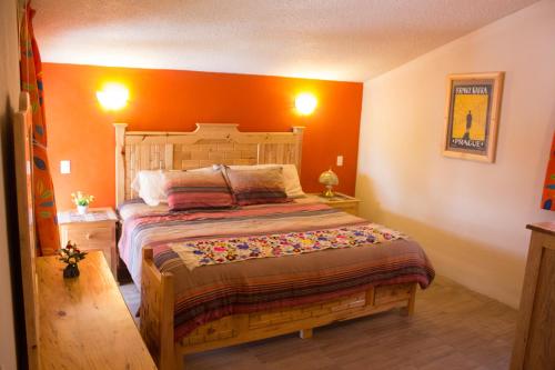 1 dormitorio con 1 cama grande y pared de color naranja en San Jose Olympia, en San Cristóbal de Las Casas