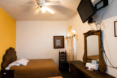 a bedroom with a bed and a mirror and a ceiling fan at Hotel María Elena in Durango