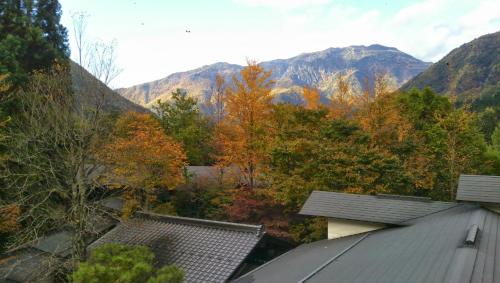 an autumn view of mountains and trees with roofs at Katsuragi no Sato in Takayama