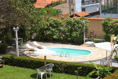 a pool with two chairs and a table and an umbrella at Pousada Vila do Mar in São Luís