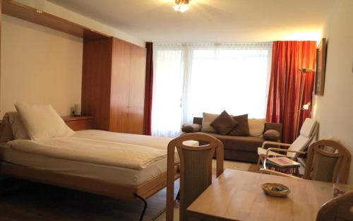 ein Schlafzimmer mit einem Bett, einem Sofa und einem Tisch in der Unterkunft Allod Bad 102 in St. Moritz