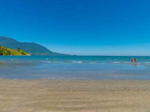 a group of people standing in the water on a beach at Pousada Vila Barequeçaba in São Sebastião