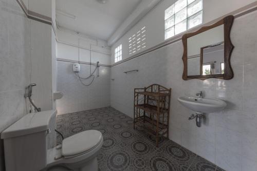 a white bathroom with a toilet and a sink at BABA Guesthouse in Don Det