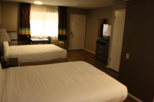 a hotel room with two beds and a television at Cozy Inn in Costa Mesa
