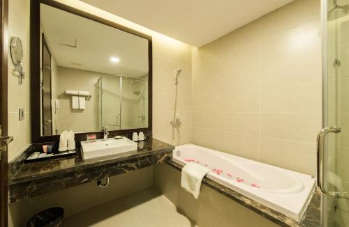 a bathroom with a tub and a sink and a mirror at Muong Thanh Hanoi Centre Hotel in Hanoi