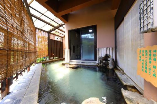 a swimming pool in the middle of a room with a building at Onyado Takasago in Ureshino